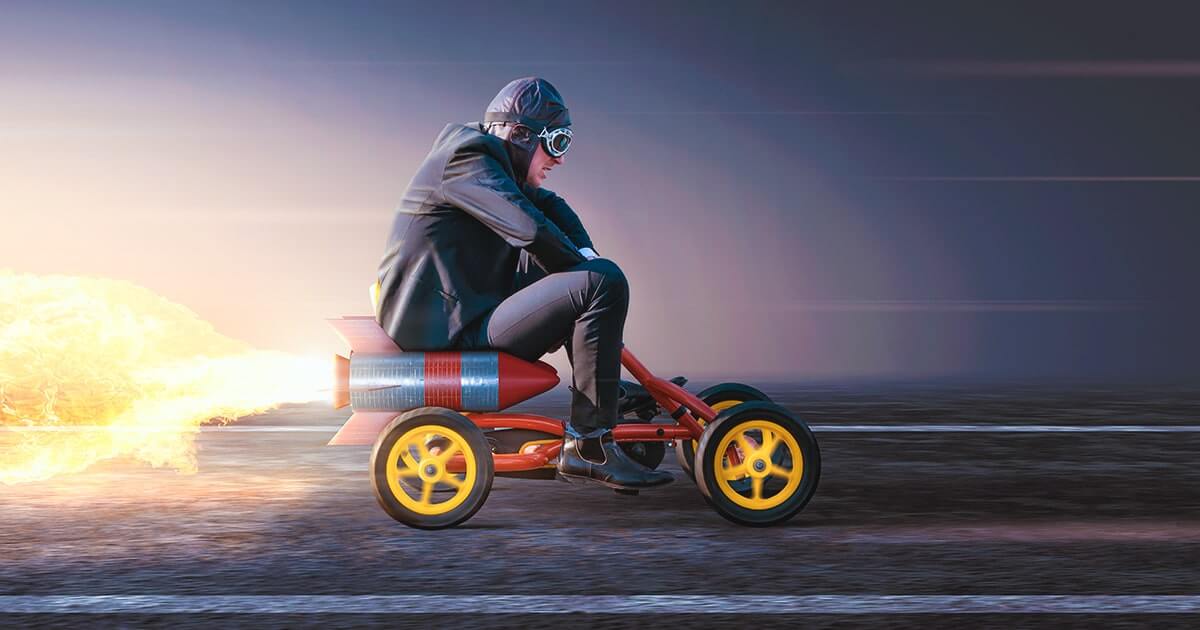 Мужчина в костюме на педальной машине с ракетным двигателем. Shutterstock.com